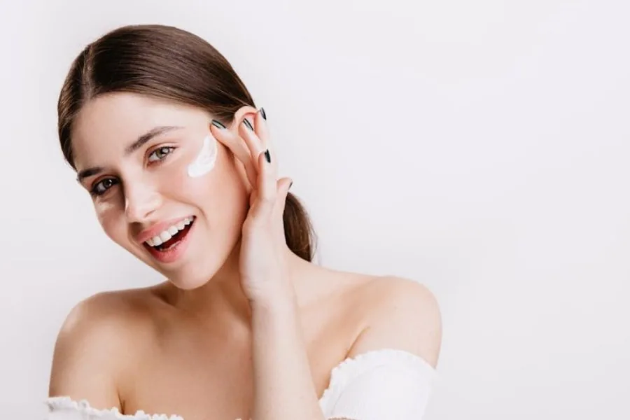 Mujer aplicándose crema facial en la mejilla